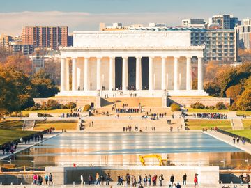 The Lincoln Memorial on a sunny autumn day in Washington, DC, with the World War II Memorial in the foreground and the reflecting pool.