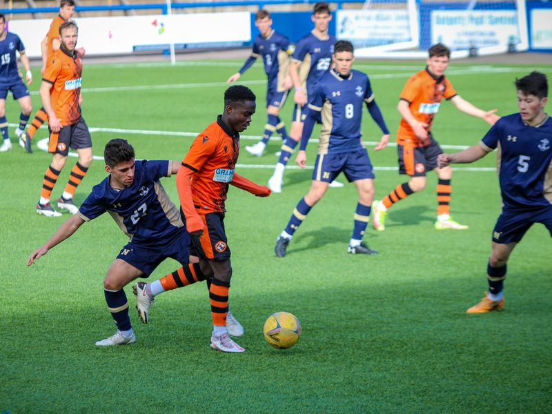 A soccer player dribbling the ball past a defender during a match.