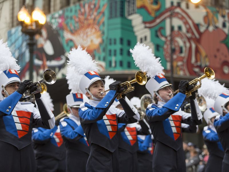 A high school marching band in blue and white uniforms playing trumpets during a parade in Chicago, Illinois.