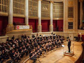 A grand concert hall filled with an orchestra and audience during a performance.