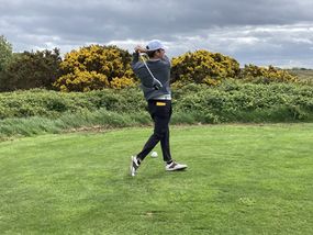 Golfer mid-swing on a lush green course