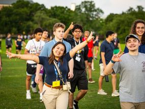 Group of teenagers and young adults walking across a field.