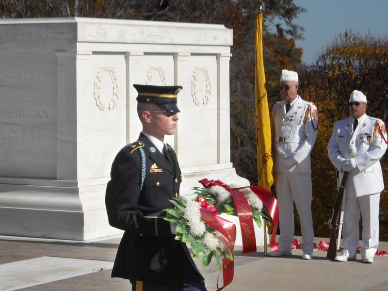 young soldier stands with a wreath in front of the tomb of the unknown soldier in the arlington national cemetery