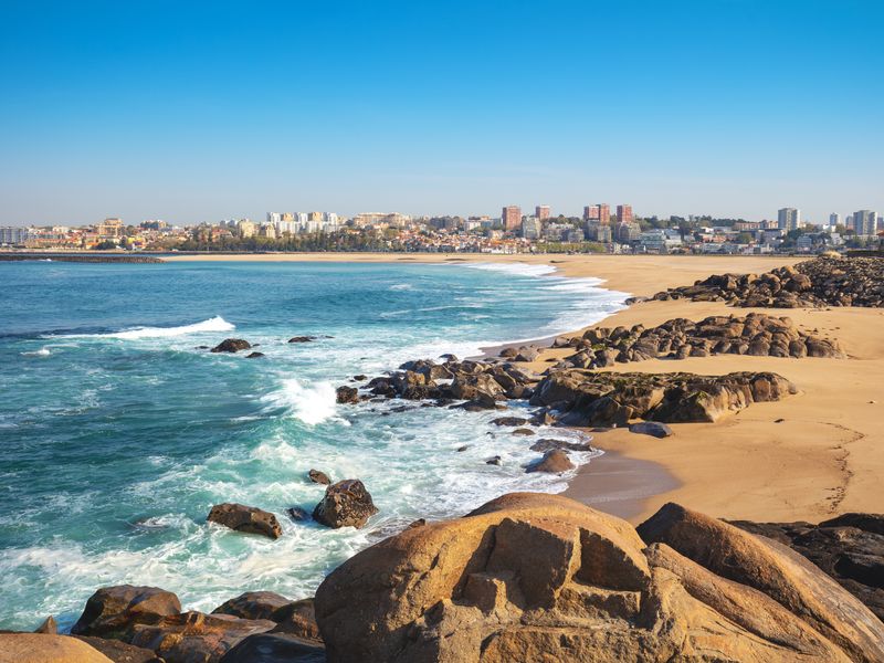 A sunny beach with a city in the background