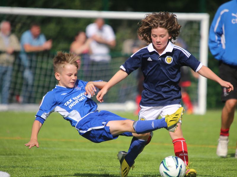 Two young soccer players competing for the ball during a game.