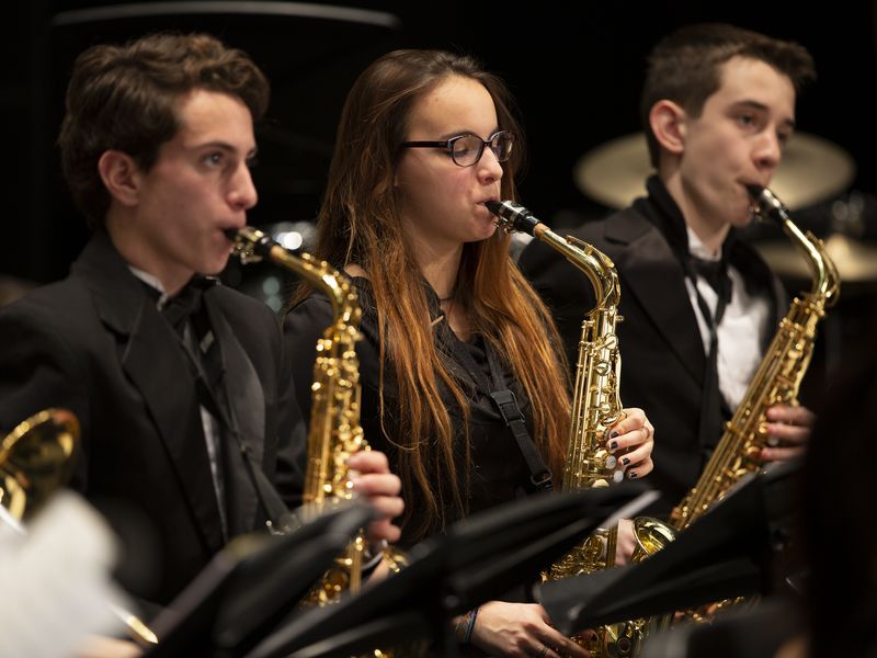 Three students playing saxophones in a school band concert