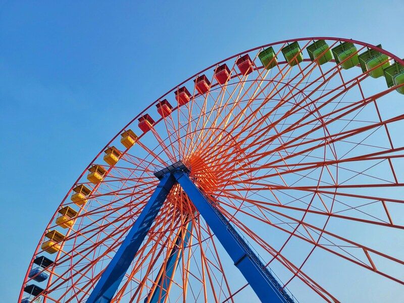 A colorful Ferris wheel against a bright blue sky.