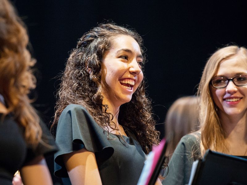 Group of smiling teenagers singing in a choir wearing black attire