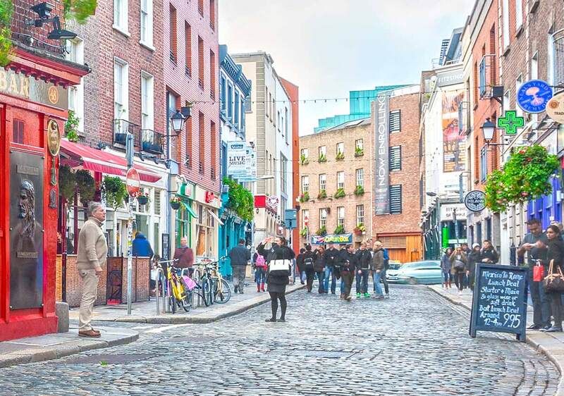 The Temple Bar pub in Dublin, Ireland, with pedestrians and characteristic architecture.