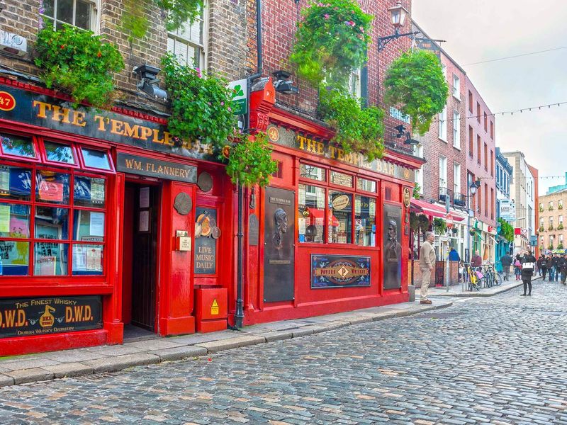 The Temple Bar pub in Dublin, Ireland, with pedestrians and characteristic architecture.