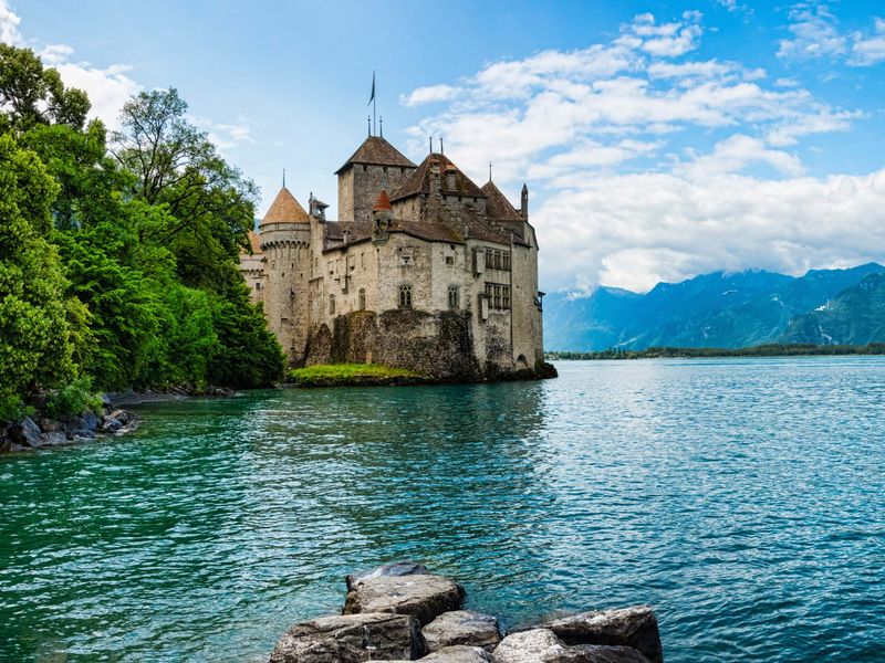 A castle on Lake Geneva, in Switzerland, with mountains in the background