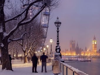 The London Eye and Big Ben lit up at twilight in the winter with snow on the ground