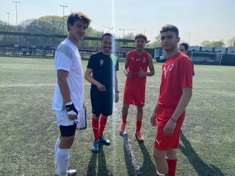 Four soccer players with a referee on a soccer field.