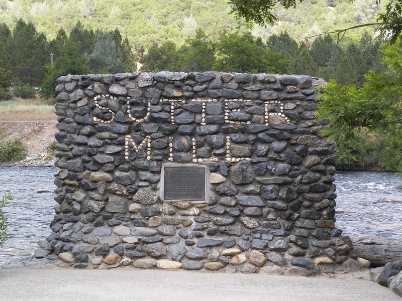 A stone monument by the river at Sutter's Mill, a significant location in the California Gold Rush.