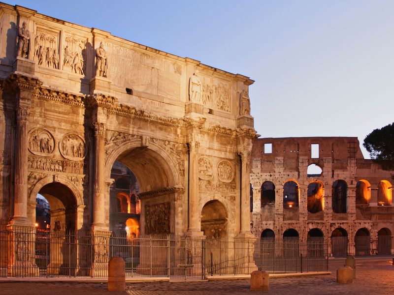 The Arch of Constantine and the Colosseum in Rome at dusk.