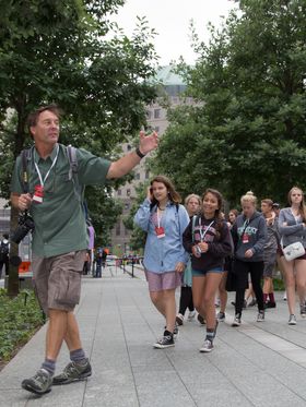 A group of teenagers on a guided walking tour in a city park.