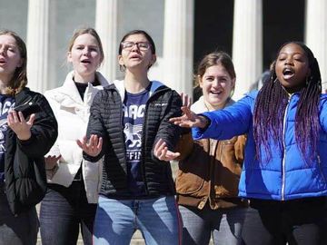 Group of teenagers singing in front of the Lincoln Memorial