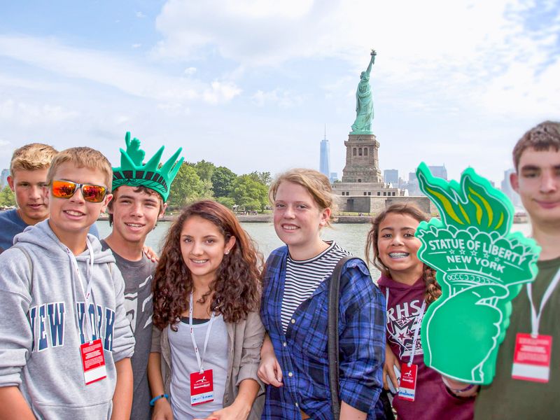 Group of teenagers on a boat tour with the Statue of Liberty in the background