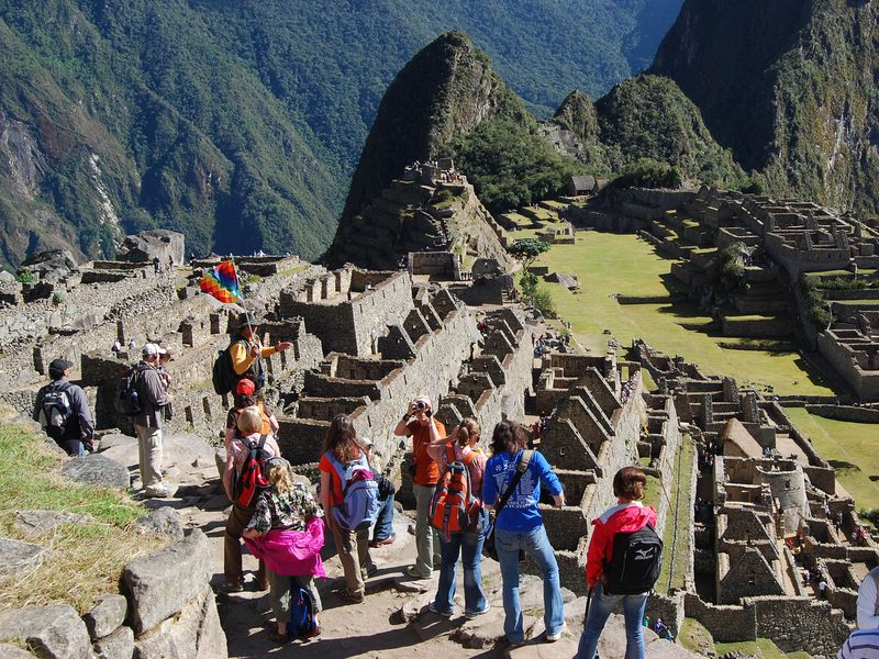 A group of tourists explores the ancient Inca citadel of Machu Picchu, perched high in the Andes Mountains of Peru.