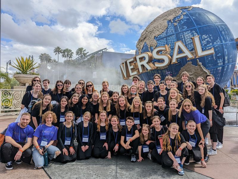 Group photo of teenagers and young adults with adults in front of the Universal Studios globe in Orlando, Florida.