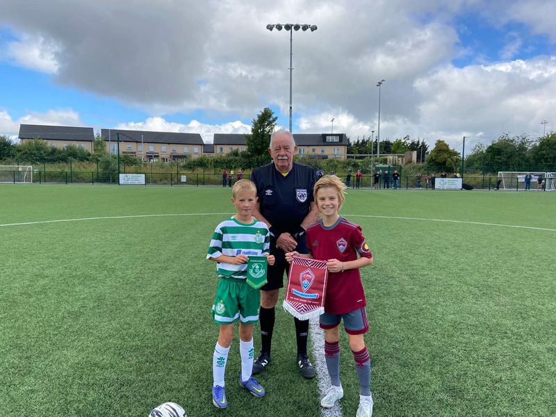 Two young soccer players and a referee on a field