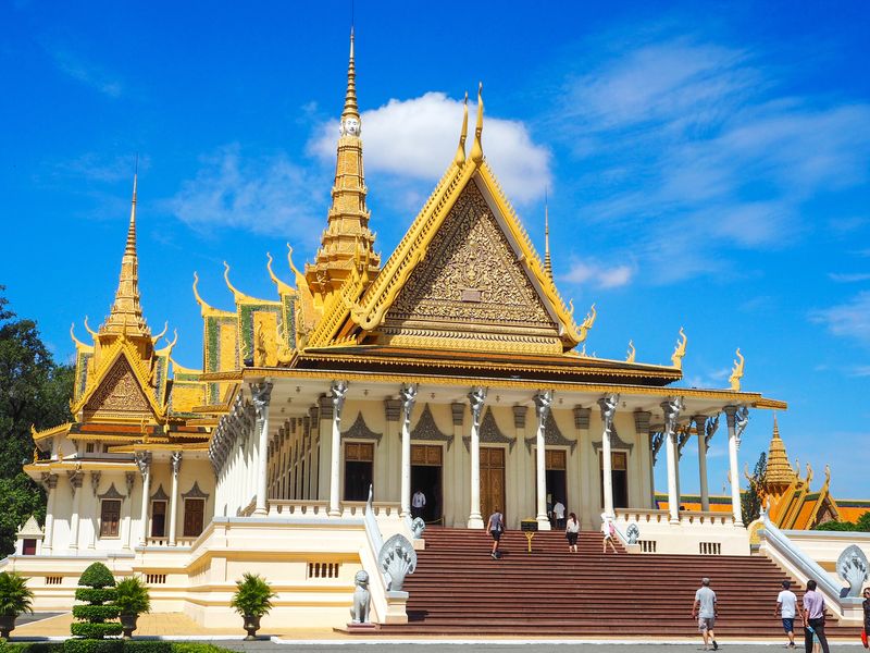 The ornate Throne Hall of the Royal Palace in Phnom Penh, Cambodia, basks in the sunlight against a clear blue sky.