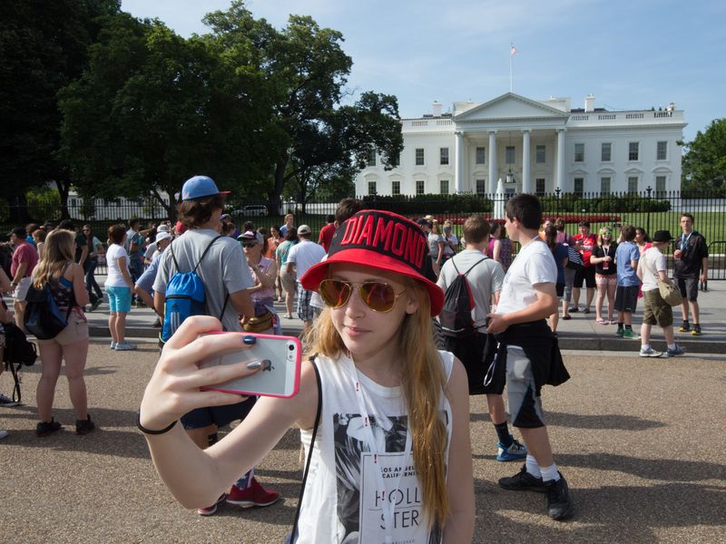 Teenage girl taking a selfie with the White House in the background.