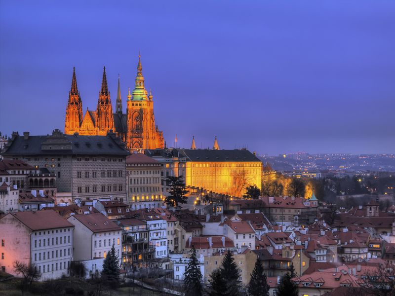 Prague Castle lit up at night, overlooking the city of Prague.