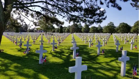 Rows of white crosses and Stars and Stripes and French flags at the Normandy American Cemetery.