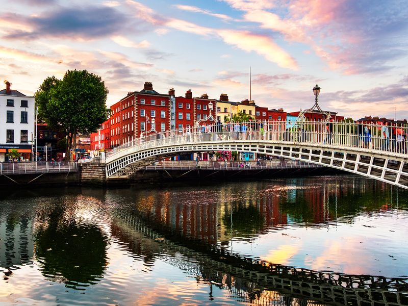 The Ha'penny Bridge illuminated by a colorful sunset in Dublin, Ireland.