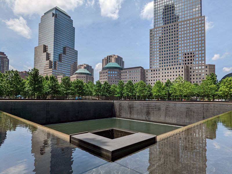 The National September 11 Memorial & Museum with reflecting pools and surrounding skyscrapers.