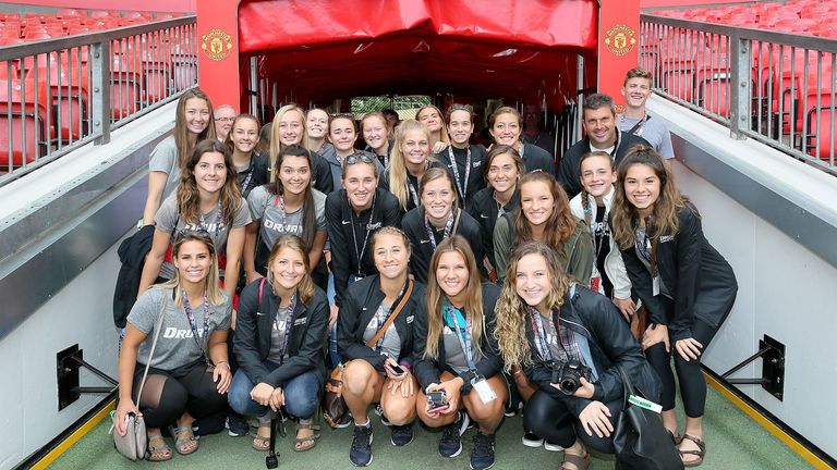 Group photo of young adult women and adults inside the tunnel at Old Trafford Stadium, home of Manchester United.