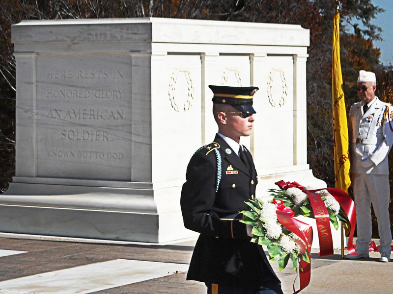 A soldier in uniform stands at attention in front of the Tomb of the Unknown Soldier.