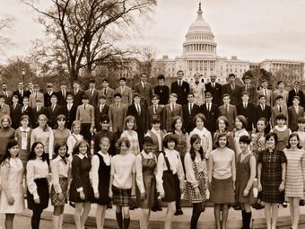 Vintage photo of a large group of teenagers and adults in formal wear, posed before the U.S. Capitol Building.