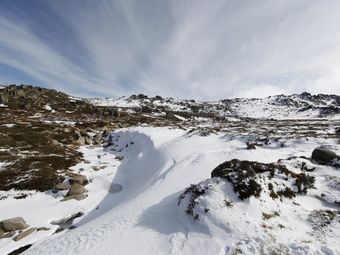 Snowy mountains with a blue sky and white clouds.