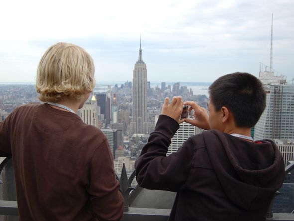 Two teenagers viewing and photographing a cityscape from a high rise building.