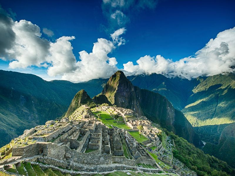 The ruins of Machu Picchu with Huayna Picchu in the background on a clear sunny day with few clouds.