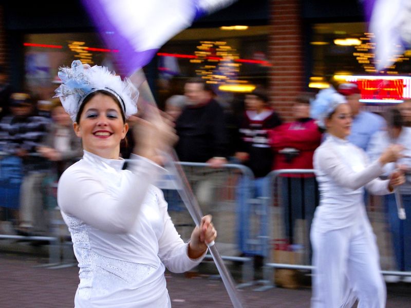 Woman in white twirling a flag in a parade