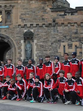 A youth soccer team poses for a photo in front of Edinburgh Castle.