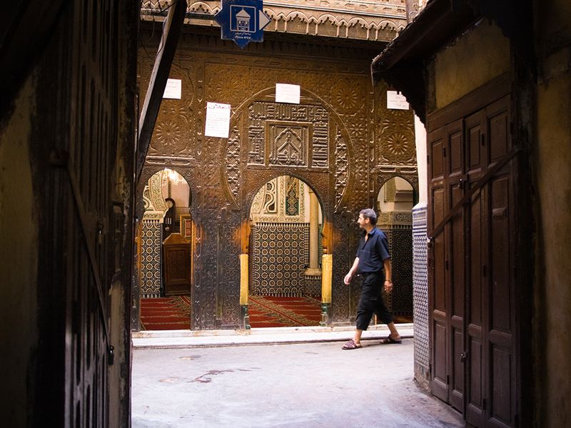 Intricate doorway in the Fes medina with a man walking by