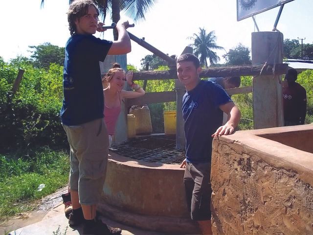 Three Young Adults Pumping Water from a Well in Africa