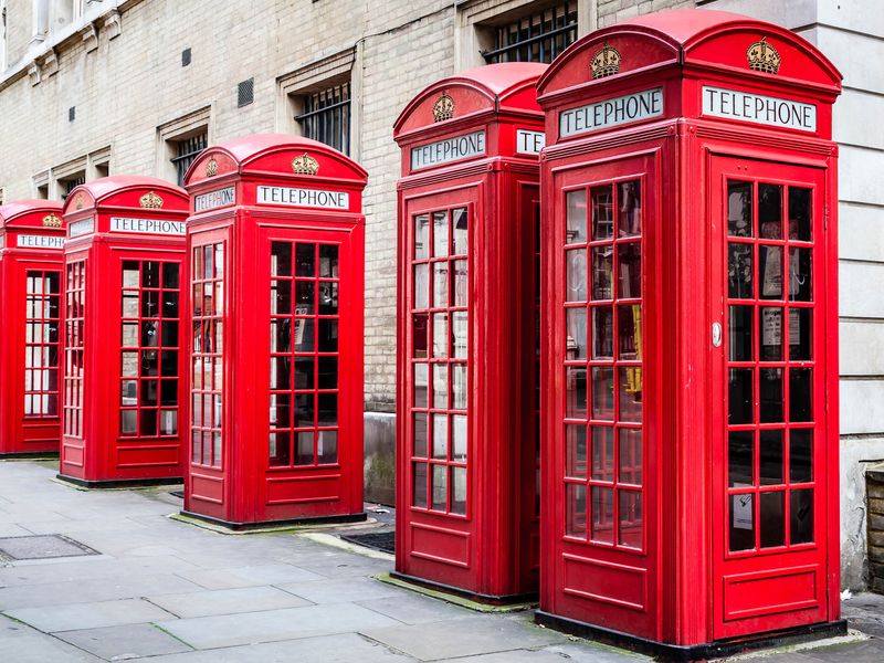 Row of iconic red telephone booths on a London street.