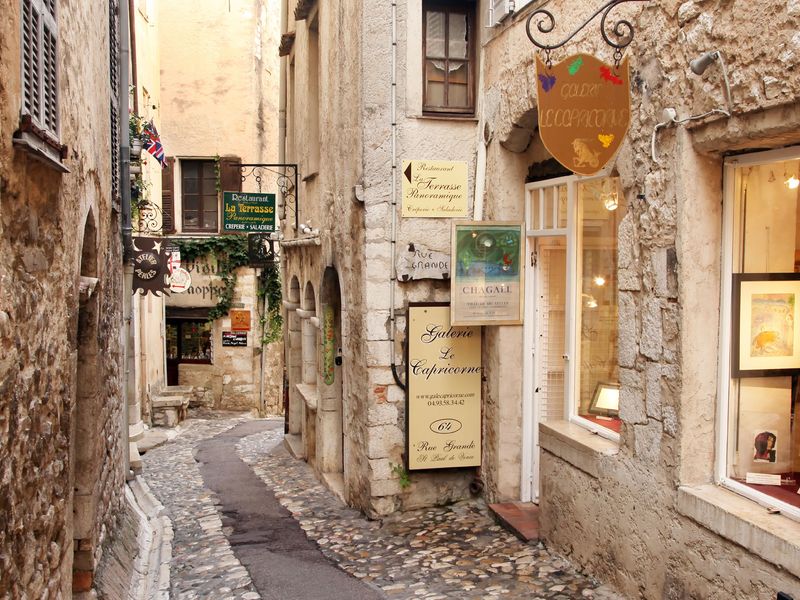 A narrow cobblestone street in Saint-Paul-de-Vence, France, lined with charming shops and restaurants.