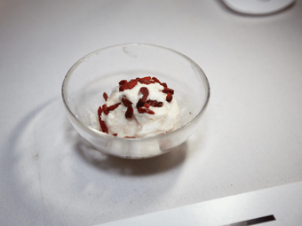 A small glass bowl containing a serving of white food topped with goji berries.