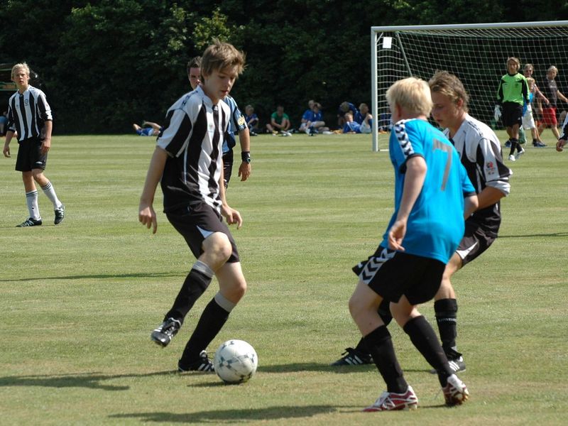 A group of teenage boys playing a soccer game on a green field.