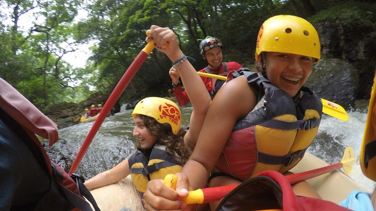 Group of teenagers happily whitewater rafting