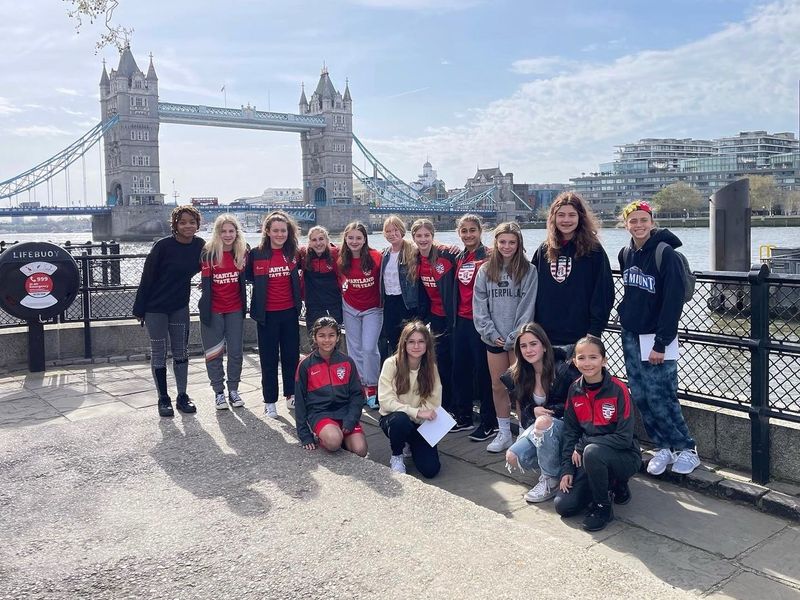 Group of teenage girls posing for a photo in front of Tower Bridge in London.