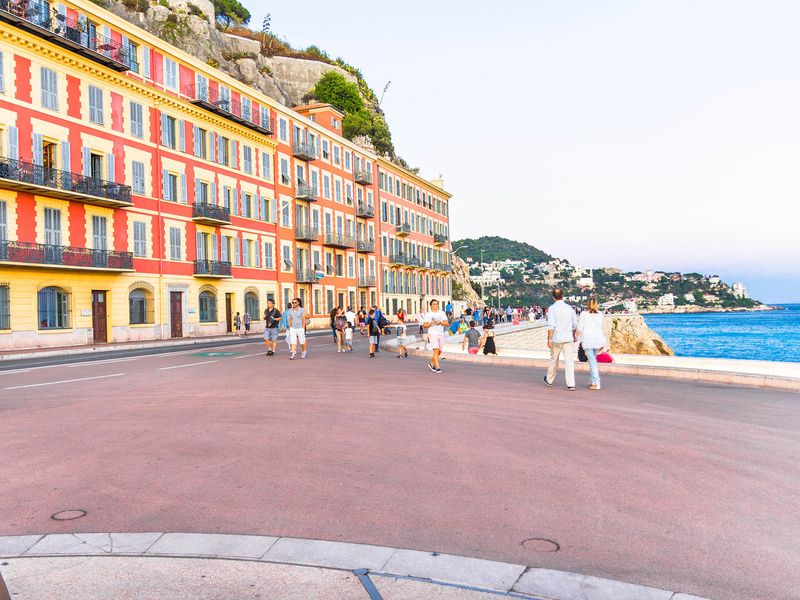 People enjoying a leisurely walk along the Promenade des Anglais in Nice, France.