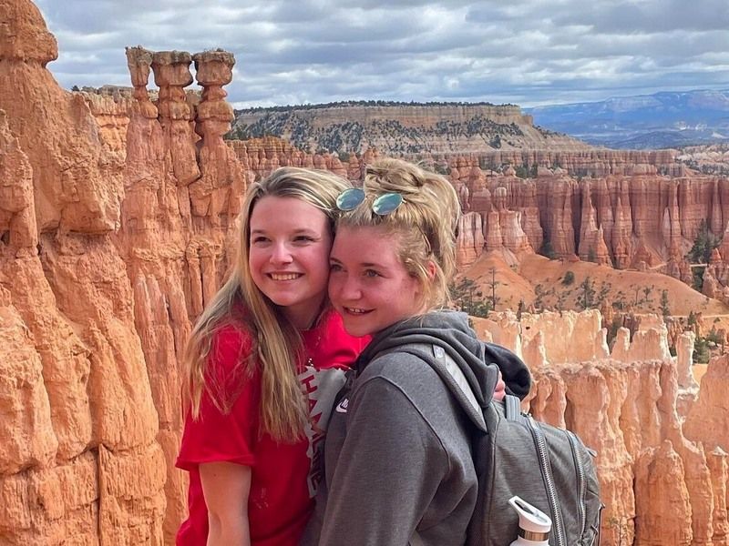 Two teenage girls pose for a photo with the breathtaking view of Bryce Canyon National Park's hoodoos in the background.