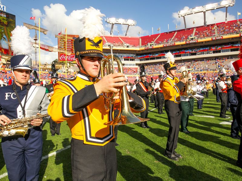 A marching band performs on a football field during halftime.